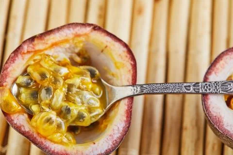 Passiflora fruit with spoon inside on a bamboo background Stock Photos