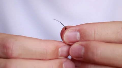 Passing a black thread through a needle eye Vídeo Stock 73506185