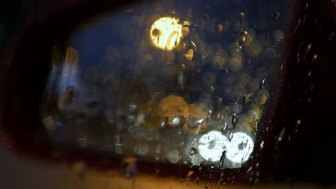 Passing car seen through window full of raindrops and rear view mirror at night Video stock 164609373
