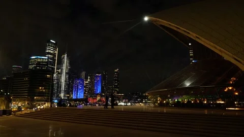 Passing diners in Sydney Opera House towards skyscrapers at night 6K Stock Footage 311141174