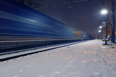 Passing freight train in blurred motion at train station on a winter night Stock Photos