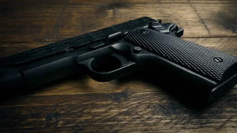 Passing Hand Gun On Table Stock Footage