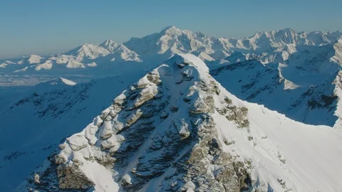 Passing by a high and snow covered mountain peak with a helicopter Stock Footage 102185174