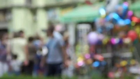 Passing people and inflatable balls out of focus in the city park Stock Footage 79325375