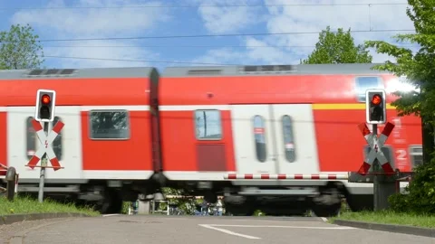 Passing red commuter train, Barriered level crossing with closed barrier, Rit Stock Footage 154625564