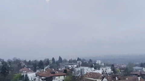 Passing residential complex, dense green forest, distant hazy mountain, cloudy Stock Footage 332834692