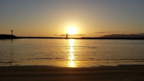 Passing sail boat during beach sunset Stock Footage 100492161