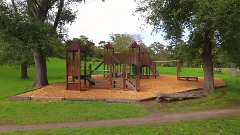 Passing A Swing Set Toward Children's Playground Equipment In Park Stock Footage 274542789