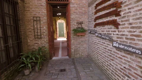 Passing through corridor leading to an old brick arch with rusty open iron gate Stock Footage 125467775