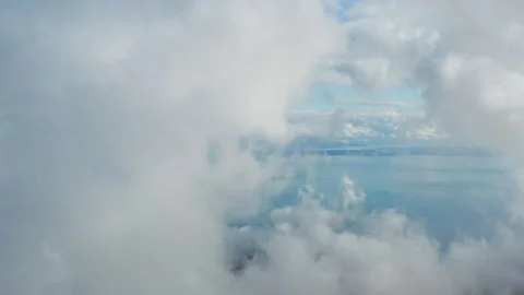 Passing throught fluffy clouds with a backdrop view of ocean and islands Stock Footage 120691864
