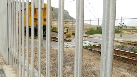 Passing train seen through a metal fence from POV of a walking person 動画素材 101691573