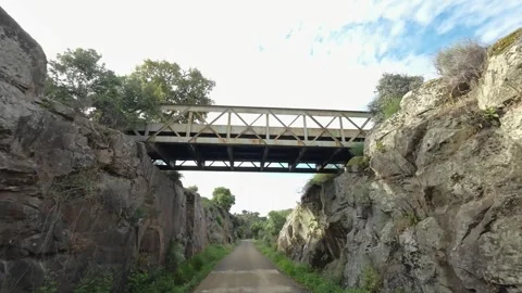 Passing under iron bridge in slow motion on the old railway route in Plasencia Stock Footage 336915863
