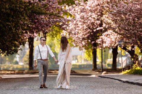 Passion and love concept. Young man and woman walking together in blooming ga Stock Photos