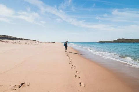 Passionate backpacker, backpack and boots in hand, walks along the Praia da I Stock Photos