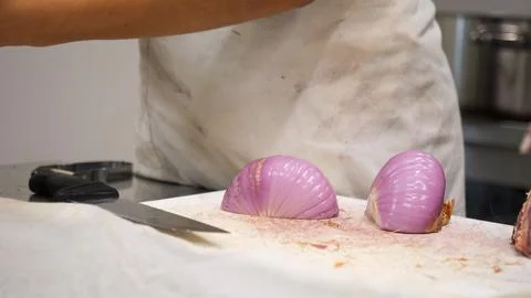 Passionate chef meticulously preparing vibrant red onions with precision in.. Stock Photos