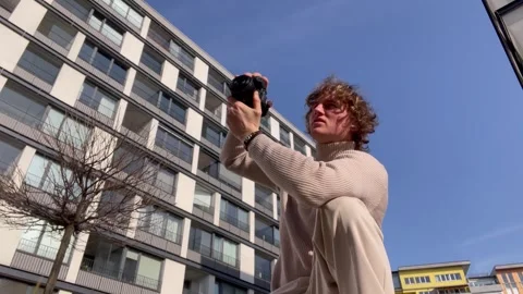 Passionate young photographer capturing architecture from a low angle, surrounde Видео 305380865
