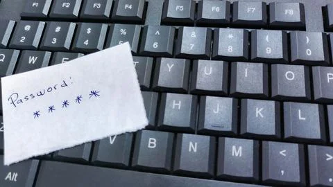 A password scribbled on a note rests on a keyboard, subtly highlighting a c.. Stock Photos