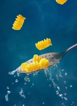 Pasta and colander on a blue background Stock Photos