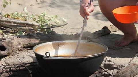 Pasta with beans is cooked in a metal cauldron on a bonfire in nature Video stock 134348396