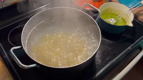 Pasta Boiling in Large Pot on Kitchen Stovetop While Sauce Cooks in Background Stock Footage 341446202