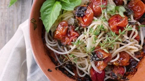 Pasta with cherry tomatoes, cheese and basil on a wooden background in a rustic Stock-Footage 148189696