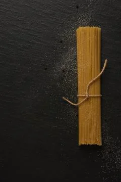 Pasta concept a bundle of long slim pasta being placed on the black backgroun Stock Photos