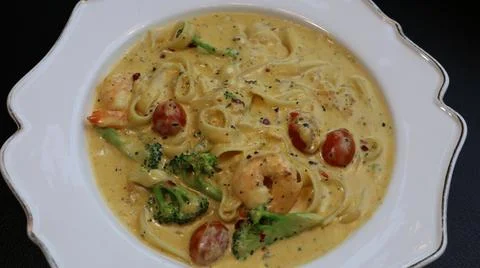 The pasta is covered in cheese and has a green sauce on top Stock Photos