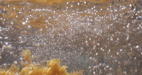 Pasta fall dawn into boiling water. Cooking pasta fusilli. Chef throws raw pasta Stock Footage 259838365