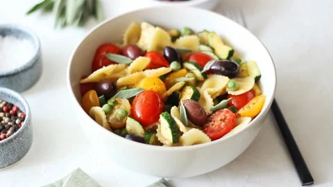 Pasta farfalle with tomatoes, zucchini, peas, Kalamata olives and sage. Vídeo Stock 202493950