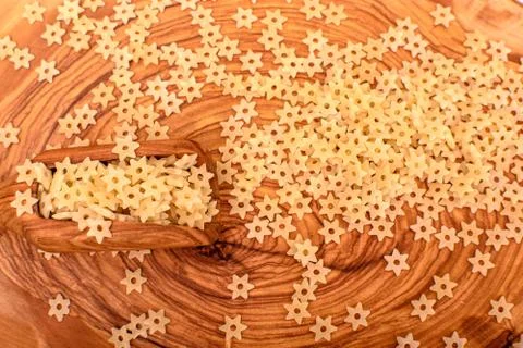 Pasta in the form of asterisks lies on an olive board and beside lies an oliv Stock Photos