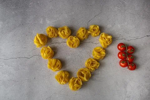 Pasta lie on the table in the shape of a big heart on a gray background Stock Photos