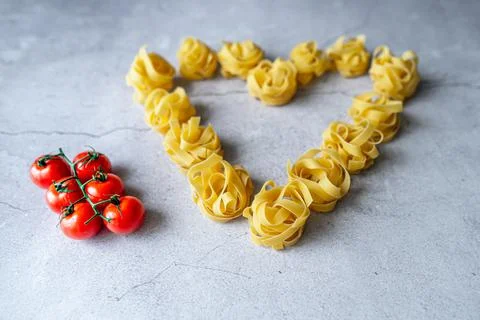 Pasta lie on the table in the shape of a big heart on a gray background Stock Photos