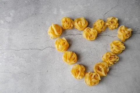 Pasta lie on the table in the shape of a big heart on a gray background Stock Photos