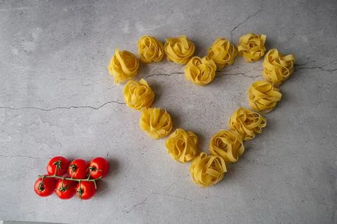 Pasta lie on the table in the shape of a big heart on a gray background Stock Photos
