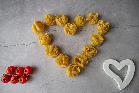 Pasta lie on the table in the shape of a big heart on a gray background Stock Photos