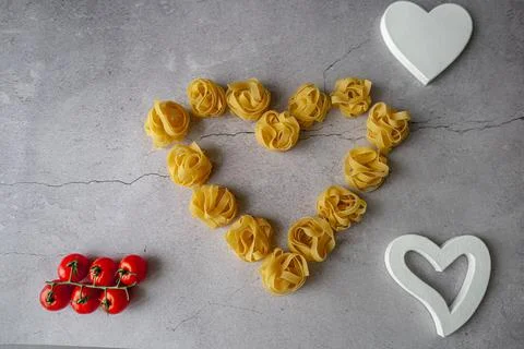 Pasta lie on the table in the shape of a big heart on a gray background Stock Photos