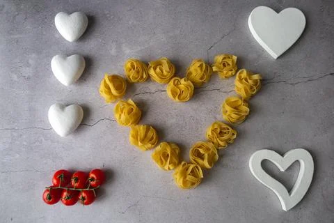 Pasta lie on the table in the shape of a big heart on a gray background Stock Photos