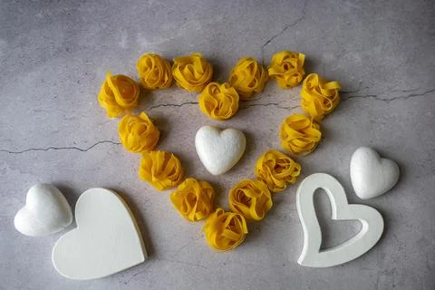 Pasta lie on the table in the shape of a big heart on a gray background Stock Photos