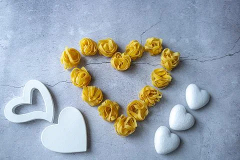 Pasta lie on the table in the shape of a big heart on a gray background Stock Photos