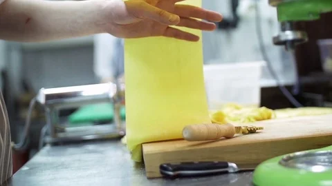 Pasta machine in working. Thin even layer of dough for pasta preparation comes Stock Footage 74718475