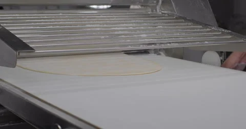 Pasta phyllo dough preparation. Fresh dough coming out of a dough sheeter in a Stock Footage 289080008