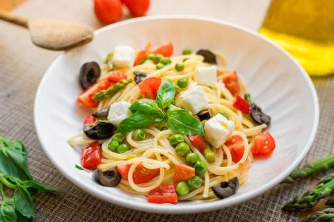 Pasta primavera spaghetti close up with cherry tomatoes, black olives, feta Stock Photos