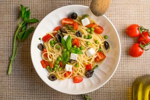 Pasta primavera spaghetti close up with cherry tomatoes, black olives, feta Stock Photos