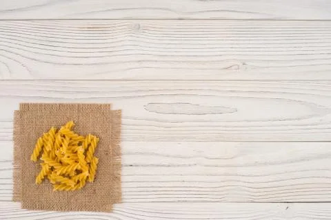 Pasta on sacking and an old white wooden table. Stock Photos