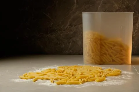 Pasta is scattered on a flour-dusted surface, showcasing its different shapes Stock Photos