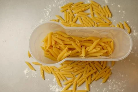 Pasta spilling out of a container on a kitchen counter during a sunny afternoon Stock Photos