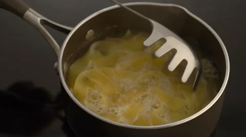 Pasta in spoon over pan on stove Stock Footage