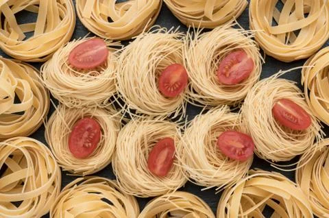 Pasta on the table, decorated with cherry tomatoes. Pasta on a dark background. Stock Photos