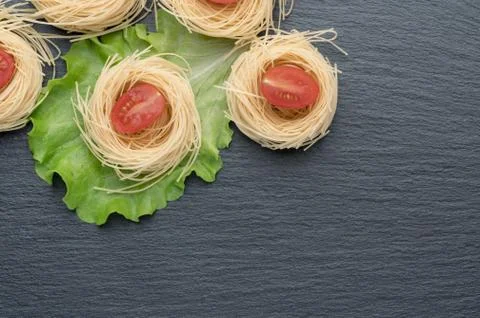Pasta on the table, decorated with cherry tomatoes. Pasta on a dark background. Stock Photos