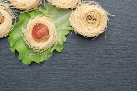 Pasta on the table, decorated with cherry tomatoes. Pasta on a dark background. Stock Photos